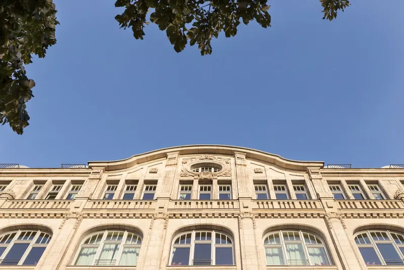 Fassade eines prächtigen Altbaus mit Rundbogenfenstern vor blauem Himmel